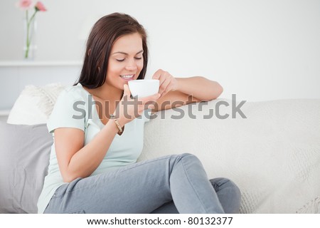 Cute dark-haired woman drinking tea in her living room