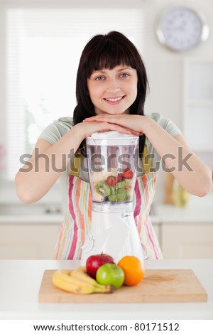 Pretty brunette woman posing with a mixer while standing in the kitchen