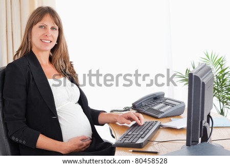 Gorgeous pregnant woman working with a computer at the office