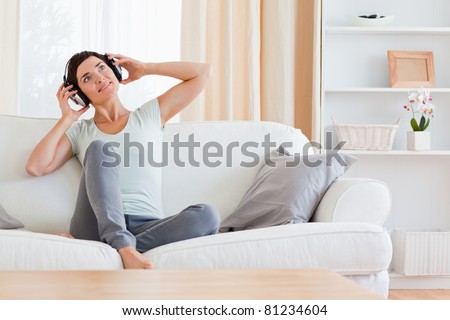 Calm brunette enjoying some music in her living room