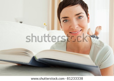 Close up of a short-haired woman with a book looking at the camera