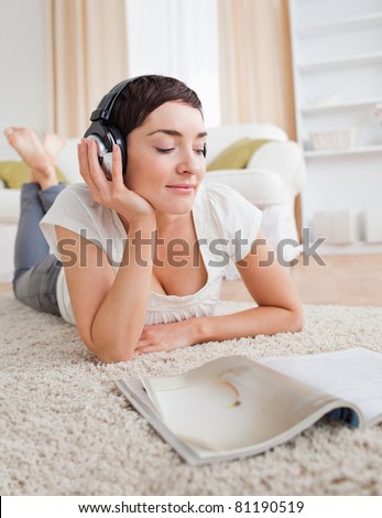 Portrait of a cute woman reading a magazine while enjoying some music in her living room