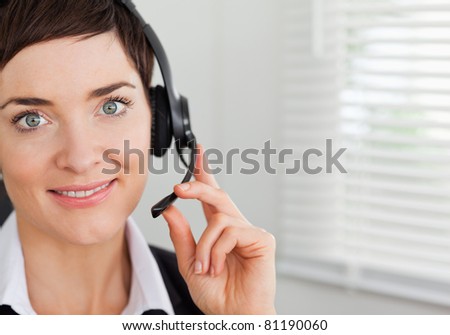 Close up of a smiling secretary calling with a headset in her office