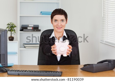 Office worker holding a piggy bank in her office