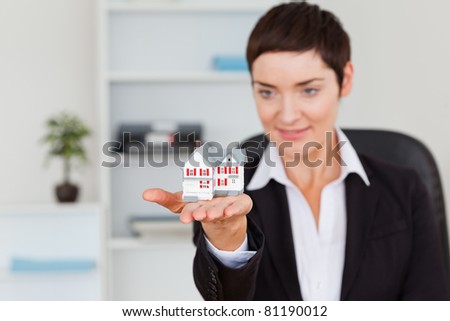 Young brunette showing a house miniature in her office