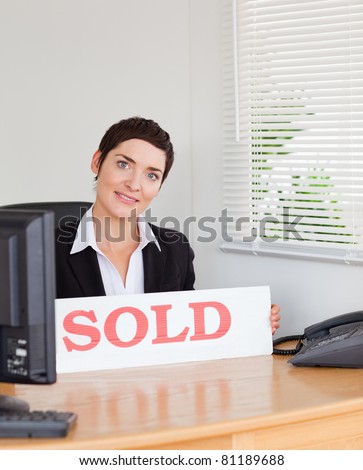 Charming real estate agent with a sold panel in her office