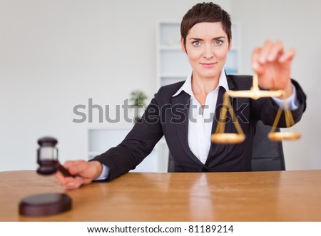 Serious woman with a gavel and the justice scale in her office