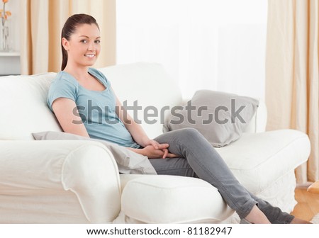 Beautiful woman posing while sitting on a sofa in the living room