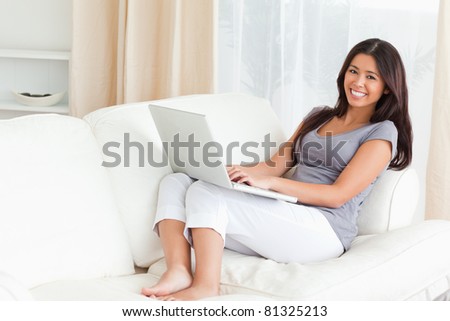 charming lady with notebook while looking at camera on sofa in living room
