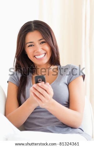 cheerful woman with mobile phone looking into camera into camera in living room