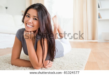 charming woman lying on a carpet smiling into camera in living room
