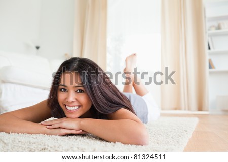 cute woman lying on a carpet smiling into camera