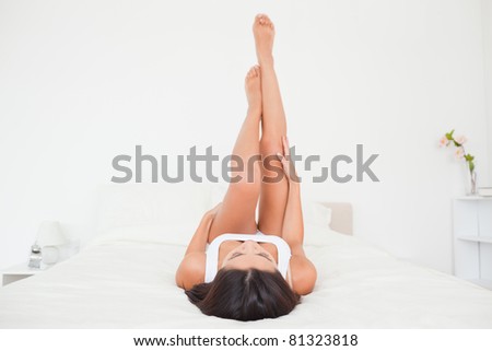beautiful woman legs raised up high lying on bed in bedroom