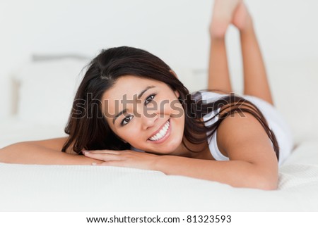 close up of a brunette woman lying on bed in bedroom with crossed legs