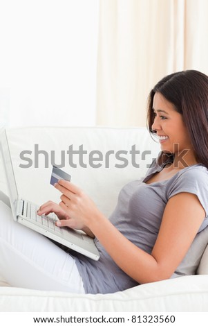 smiling woman working with notebook holding card in her hands being in living room