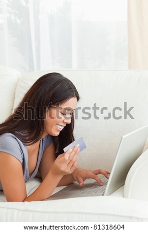 charming woman with card in hand lying on sofa in living room