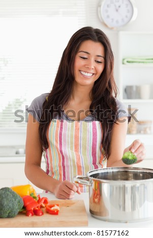 Good looking woman preparing vegetables while standing in the kitchen