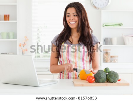 Good looking woman relaxing with her laptop while standing in the kitchen