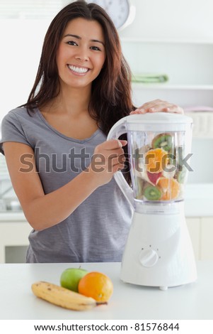 Good looking woman using a blender while standing in the kitchen