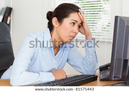 Beautiful upset woman looking at a computer screen while sitting at the office