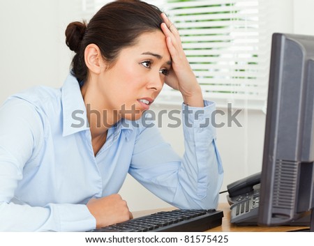 Attractive upset woman looking at a computer screen while sitting at the office