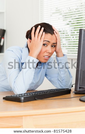 Pretty upset woman looking at a computer screen while sitting at the office