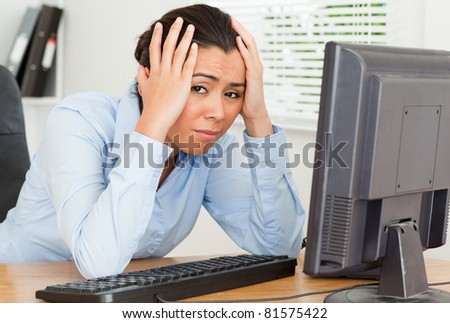 Lovely upset woman looking at a computer screen while sitting at the office