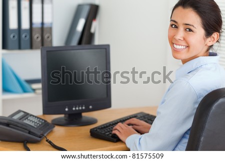 View from behind of a good looking woman typing on a keyboard while working at the office