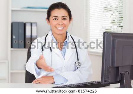 Pretty female doctor inviting somebody to seat while looking at the camera in her office