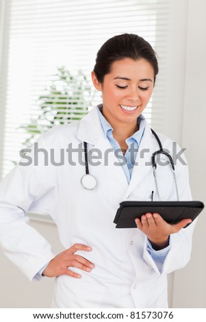 Attractive female doctor with a stethoscope holding a notebook while standing in her office