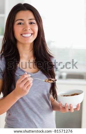 Gorgeous female enjoying a bowl of cereal while standing in the kitchen