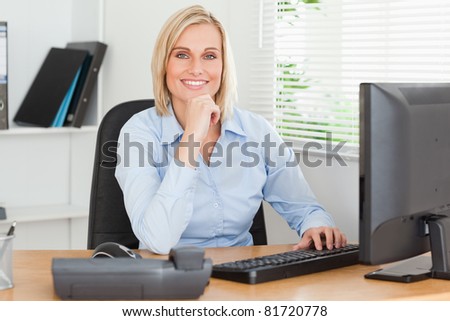 Working cute woman in front of a screen looking into camera in an office