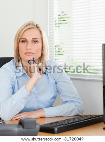 Serious thoughtful looking woman behind her desk looking into camera in her office