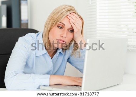 Blonde business woman touching her forehead being tired in her office