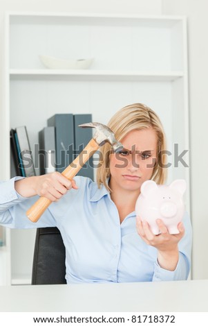 Angry woman wanting to destroy her piggy bank in her office
