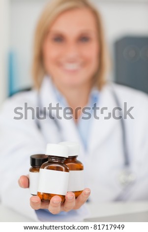 Smiling blonde doctor holding medicine in her office