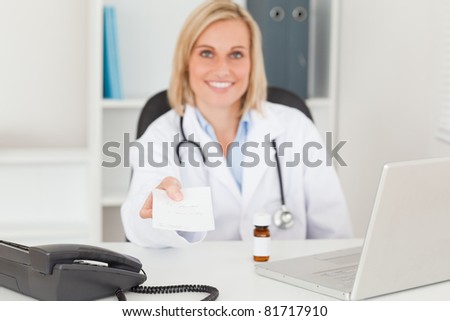 Smiling doctor holding prescription in her office