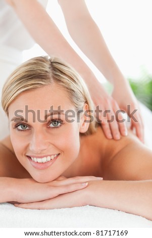 Close up of a smiling woman relaxing on a lounger during a massage in a wellness center