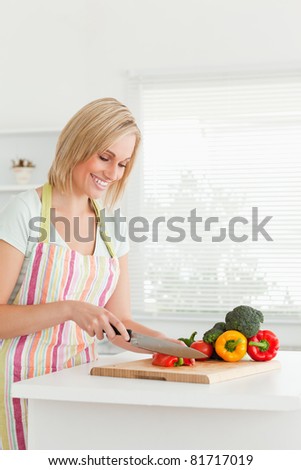 Gorgeous woman cutting red pepper in kitchen