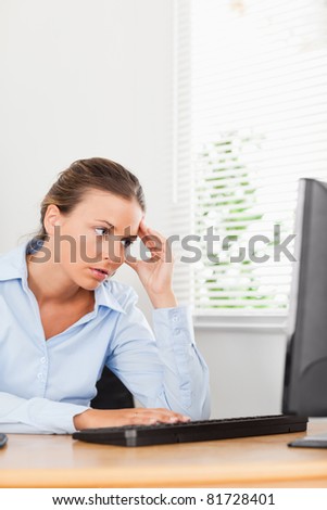 A frustrated looking businesswoman is looking to the screen of her pc in an office