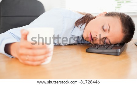 A businesswoman is sleeping with her head on the keyboard in an office