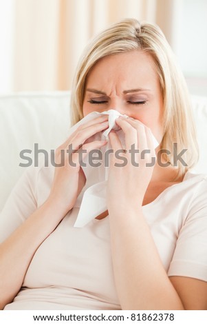 Portrait of an ill woman blowing her nose in her living room