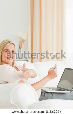 Portrait of a smiling woman paying her bills on line with her thumb up