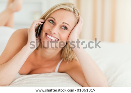 Close up of a smiling woman answering the phone in her bedroom