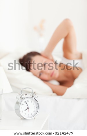 Close up of a good looking red-haired woman lying in bed not wanting to hear the alarm clock