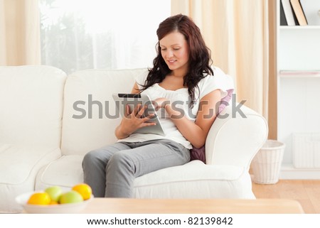 Young red-haired woman holding a tablet in her living room