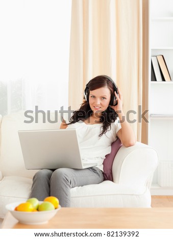 Cute woman with a notebook listening to music in her living room