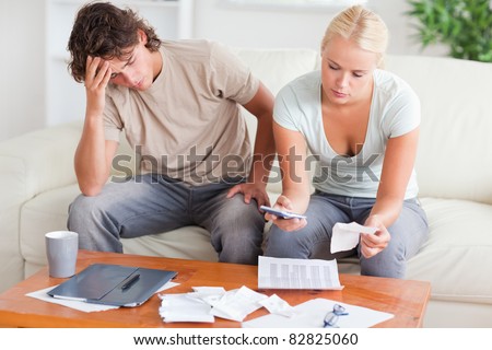 Stressed couple calculating their expenses in the living room