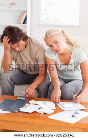 Despaired worn out couple calculating their expenses in the living room