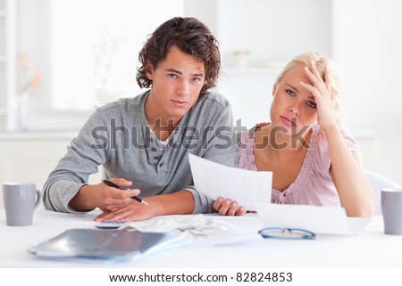 worried couple listing expenses in the living room